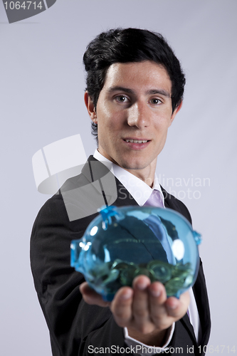 Image of Businessman holding a piggybank full of coins