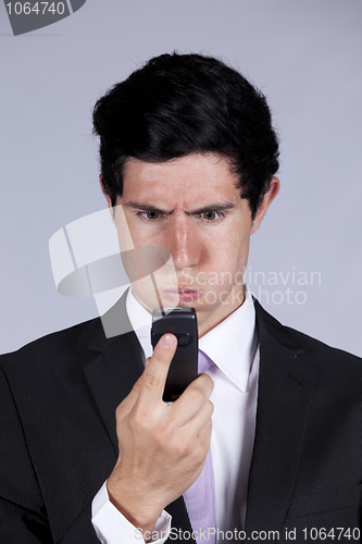 Image of Angry businessman looking to his cellphone