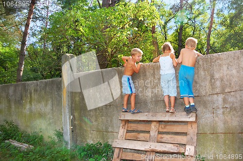 Image of curious children spying over the fence