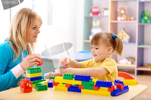 Image of Teacher and preschooler play with building bricks