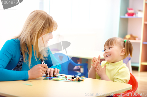 Image of Teacher and little girl play with plasticine