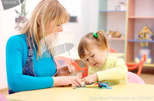 Image of Teacher and little girl play with plasticine