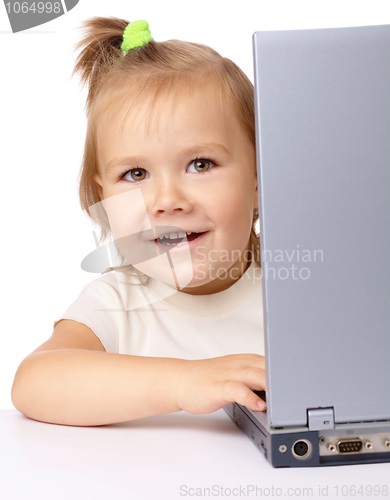 Image of Cute little girl is looking out from her laptop