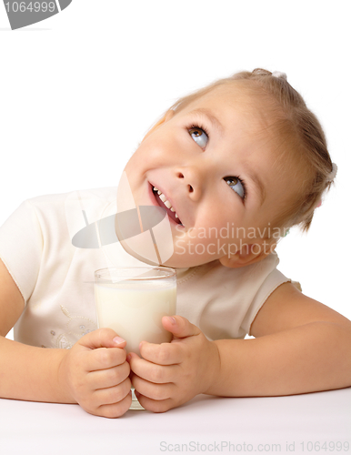 Image of Little girl with a glass of milk looks up