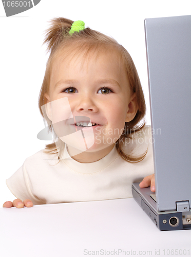 Image of Cute little girl is looking out from her laptop
