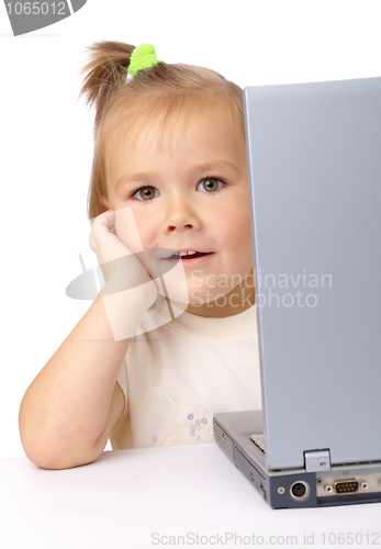 Image of Cute little girl is looking out from her laptop