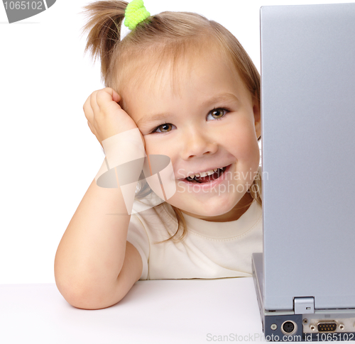 Image of Cute little girl is looking out from her laptop