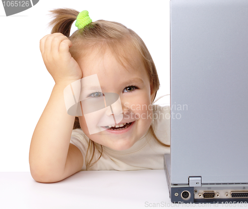 Image of Cute little girl is looking out from her laptop