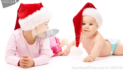 Image of Two children wearing red Christmas caps and smile