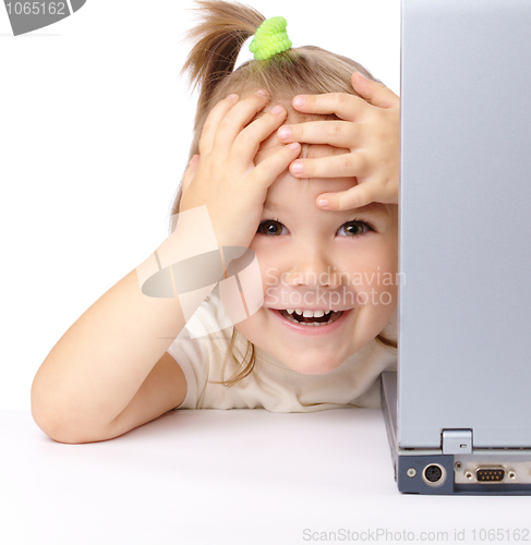 Image of Cute little girl is looking out from her laptop