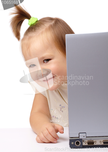 Image of Cute little girl is looking out from her laptop
