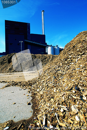 Image of bio power plant with storage of wooden fuel against blue sky