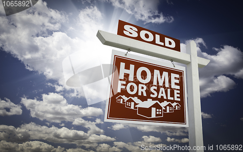 Image of Red Sold Home For Sale Real Estate Sign Over Clouds and Sky