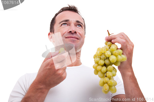 Image of handsome man eating a green grapes