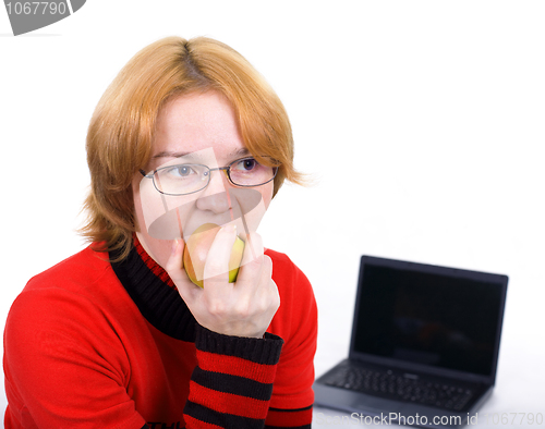 Image of The woman bites an apple against the laptop