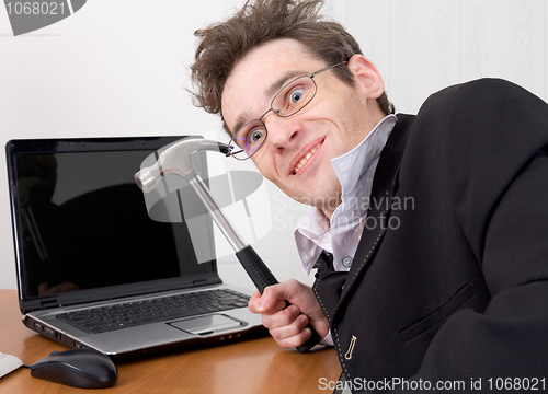 Image of Businessman in spectacles gone mad with a hammer