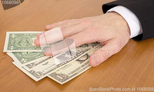 Image of Man's hand over dollars