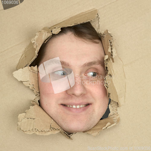 Image of Male face look up from hole in carton