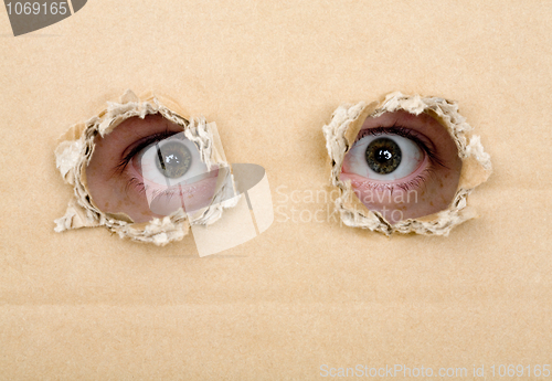 Image of Eye looking from a holes in a cardboard