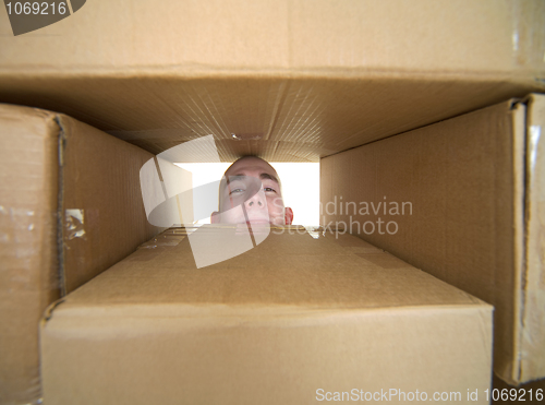 Image of Face looking trough window in pile cardboard boxes