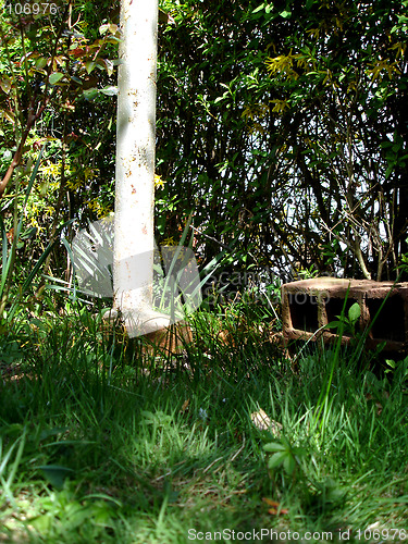 Image of Rusty pole with clay brick on bright green grass