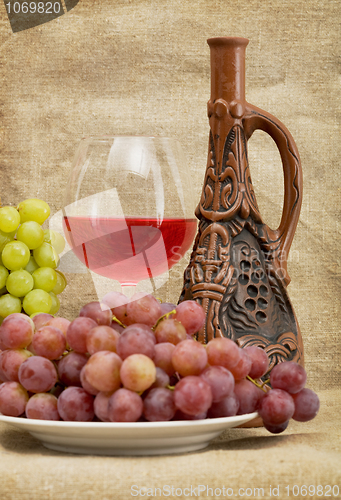 Image of Ceramic bottle, grapes and red wine