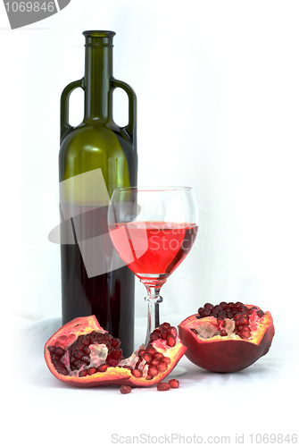 Image of Glass of wine, bottle and a red pomegranate