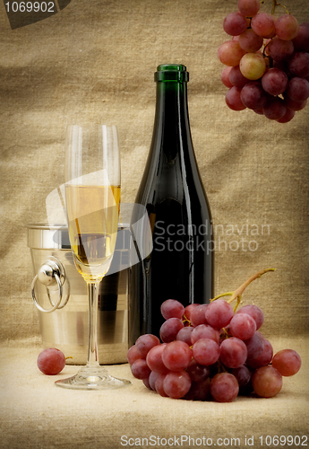 Image of Champagne bottle, bucket, goblet and grapes