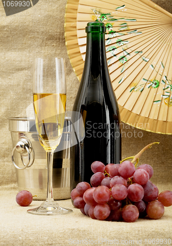 Image of Champagne bottle, bucket, goblet and grapes