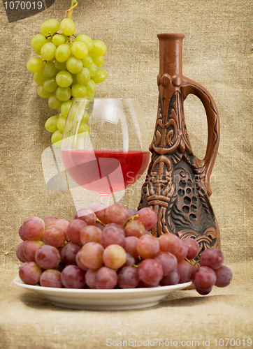 Image of Ceramic bottle, grapes and red wine