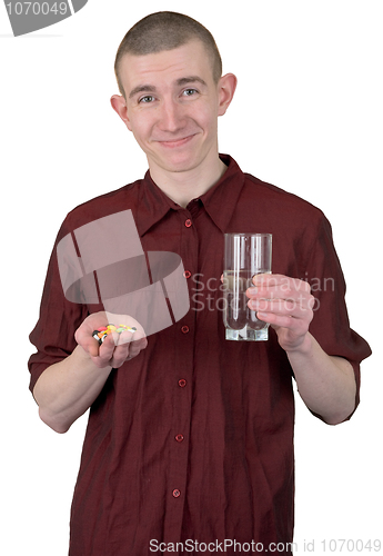 Image of Young man with glass of water and tablets