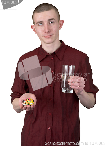 Image of Young man with glass of water and tablets