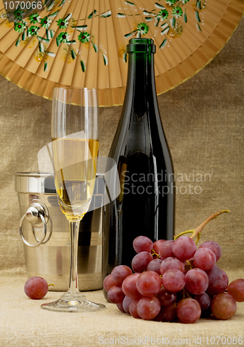 Image of Champagne bottle, bucket, goblet and grapes