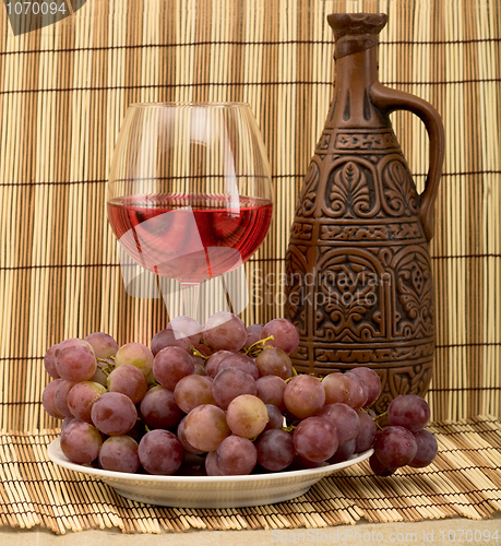 Image of Carafe, grape and goblet on mat