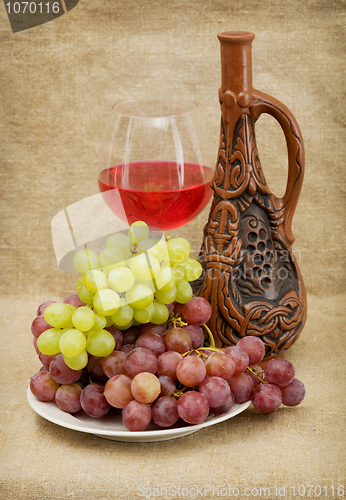 Image of Ceramic bottle, grapes and red wine