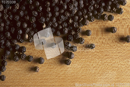 Image of Whole black peppercorns on butcherblock