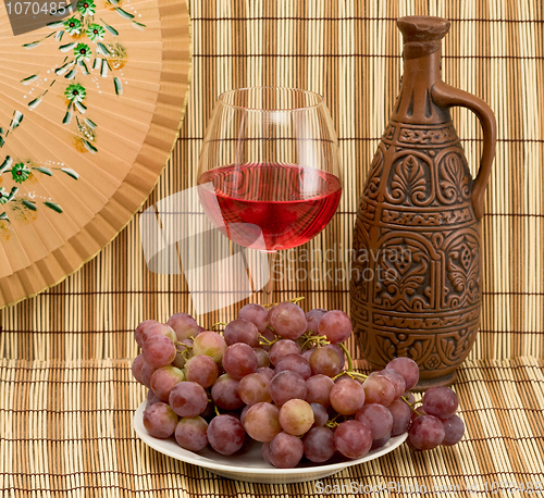 Image of Bottle, bucket, goblet and grapes