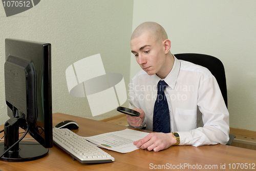 Image of Businessman with a magnifier on a workplace