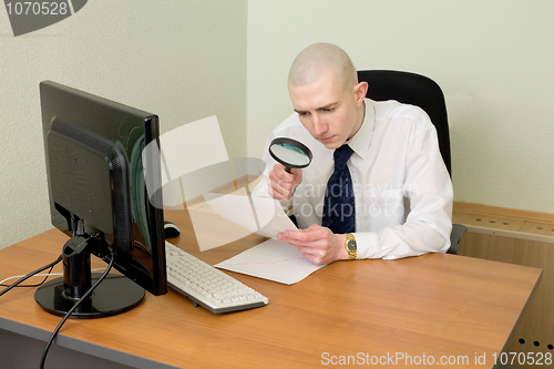 Image of Businessman with a magnifier on a workplace