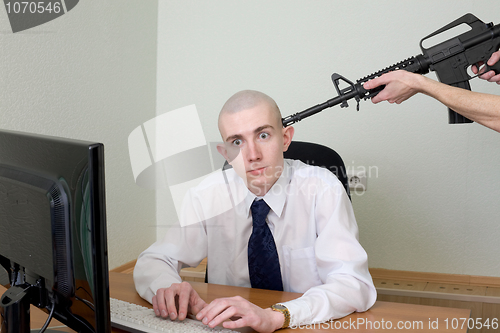 Image of Man at office with a rifle near a head