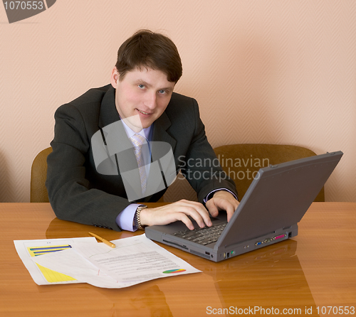 Image of Businessman sits at table with the laptop