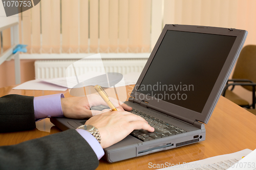 Image of Laptop and hands with a pen