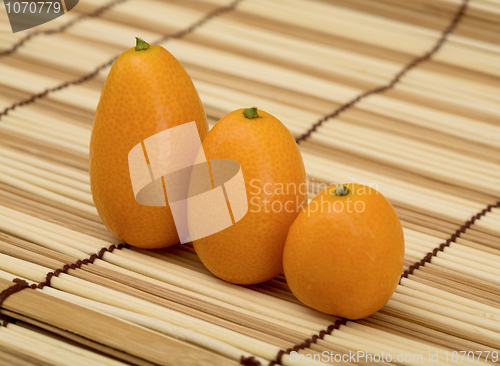 Image of Three fresh kumquat against a mat