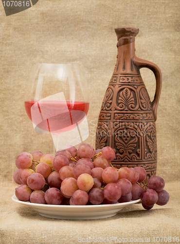 Image of Ceramic bottle, goblet and grapes