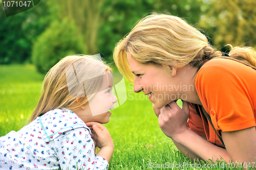 Image of Young mother and daughter laying on the grass