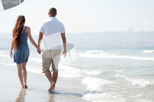 Image of young couple walk at the beach