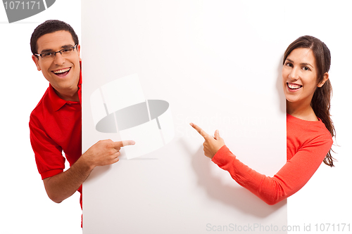 Image of Happy young couple pointing to copy space