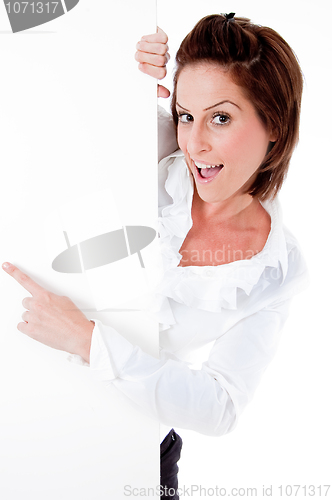 Image of Happy young female holding a blank billboard, pointing at it