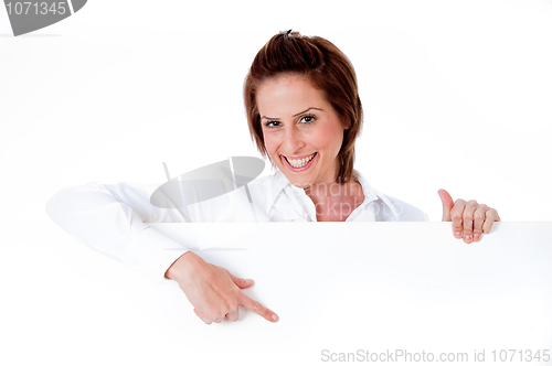 Image of Happy young female holding a blank billboard, pointing at it
