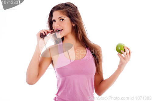 Image of sexy girl biting a chocklate and keep the apple in other hand